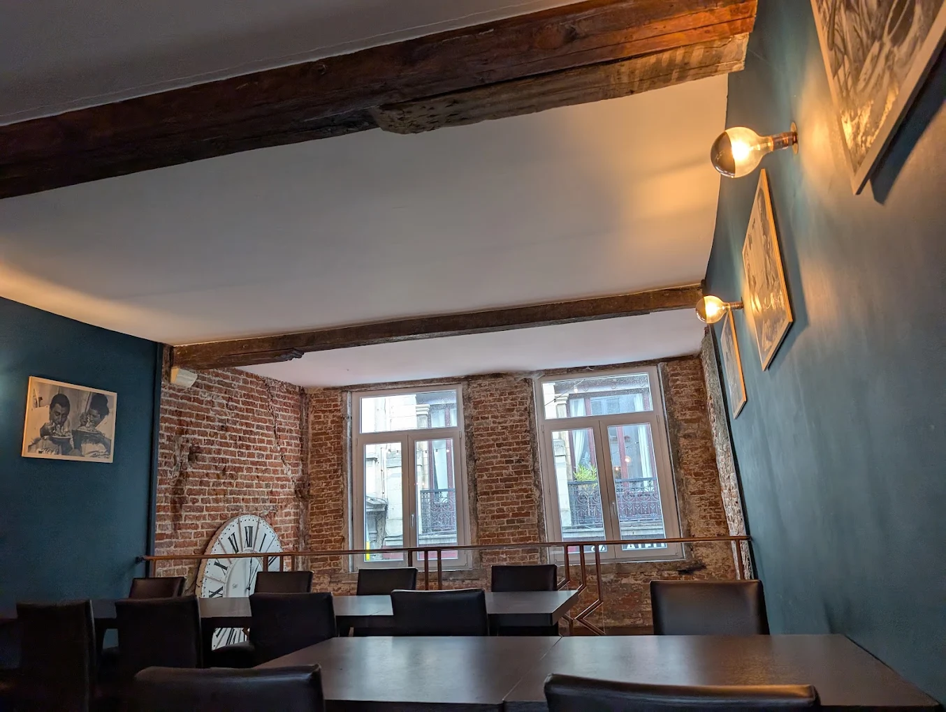Sala al primo piano con muri in mattoni, finestre sulla strada e orologio d'epoca