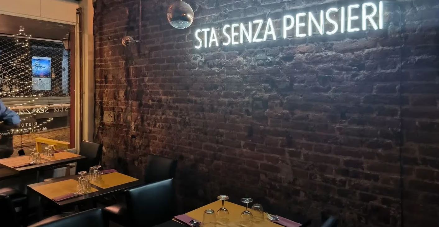 Insegna al neon con la scritta Sta Senza Pensieri sul muro di mattoni